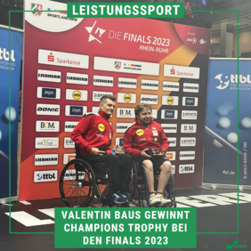 Das Bild zweigt zwei Sportler vor der Sponsorenwand der Finals 2023. Sie halten die Trophäe in den Händen und lächeln in eine Kamera.